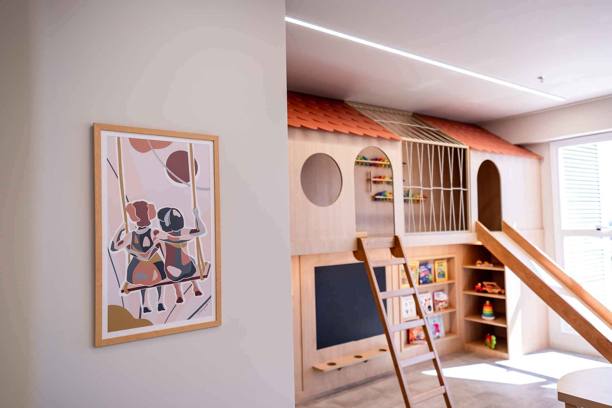 Corredor de entrada com quadro decorativo e área lúdica ao fundo